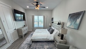 A bedroom with a bed, bedside tables, a ceiling fan, a TV, a window with curtains, a painting, and a rug. - Spacious 5-bedroom townhome in charming Treasure Island with Rooftop Hot tub (Treasure Island)