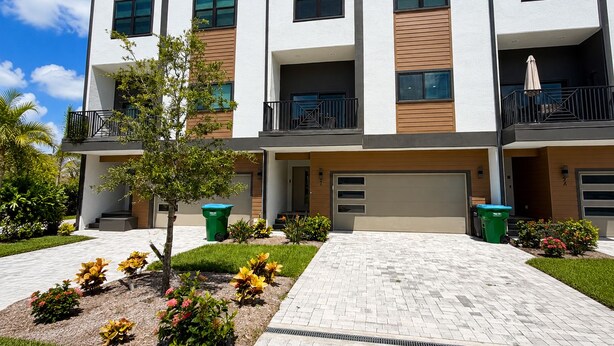 A modern multi-story residential building with balconies, a paved driveway, and landscaped gardens. - Spacious 5-bedroom townhome in charming Treasure Island with Rooftop Hot tub (Treasure Island)