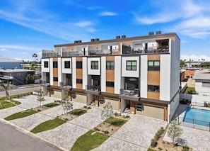 Un moderno edificio residenziale a più piani con balconi, una piscina e un giardino curato.