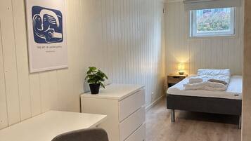 A bedroom with a bed, bedside table, lamp, and a poster on the wall.