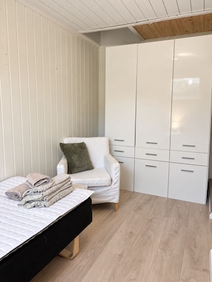 Une chambre à coucher avec un lit, une chaise, une armoire et un plancher en bois.