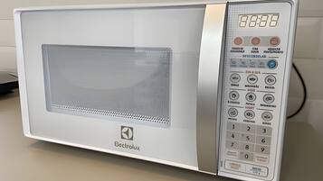 Um micro-ondas branco com visor digital e painel numérico.