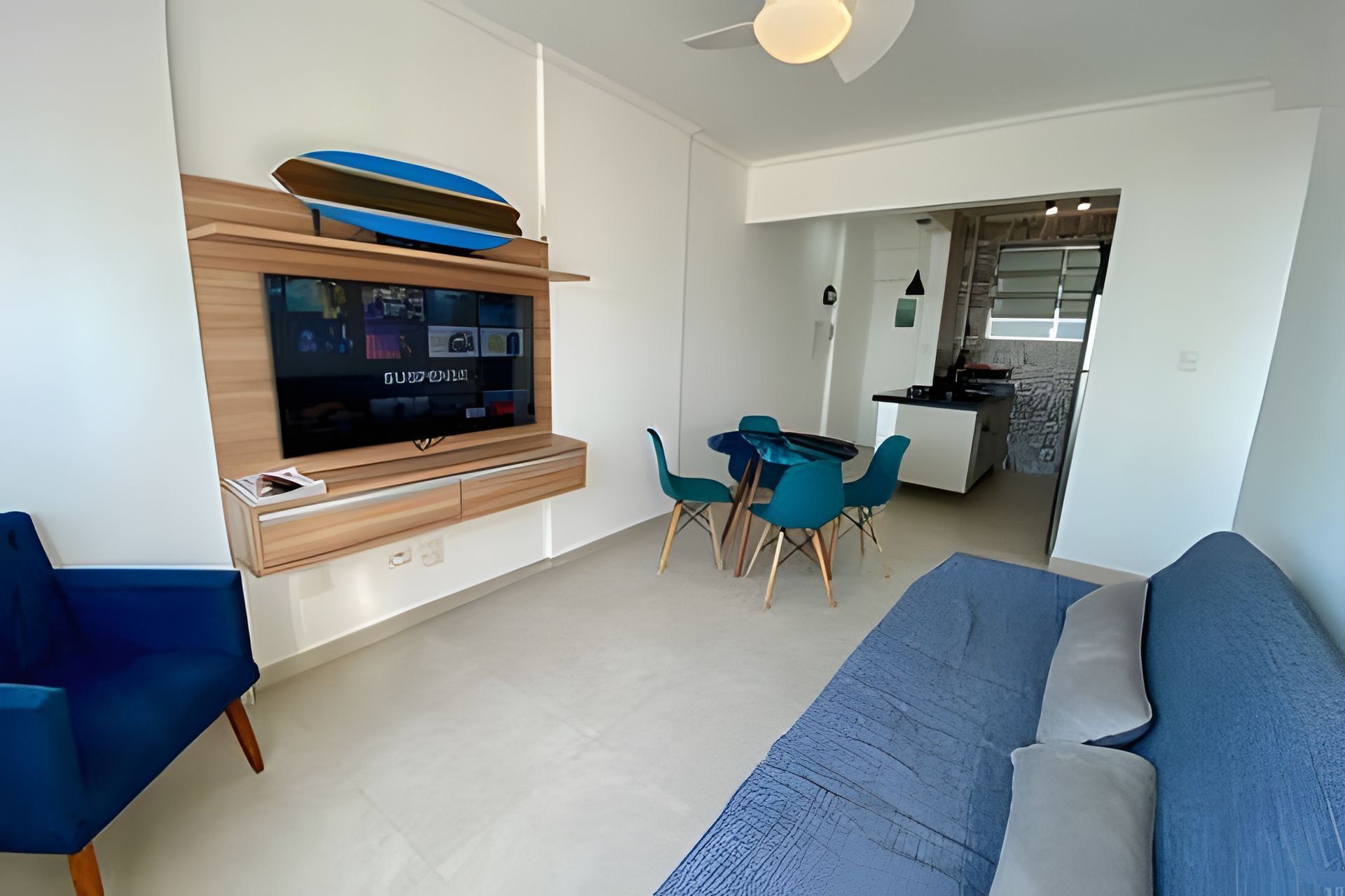 Una sala de estar moderna con un televisor de pantalla plana, un sofá azul y sillones color turquesa.