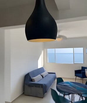 Uma sala de estar moderna com um sofá, uma mesa de jantar e uma grande janela com vista para o mar.