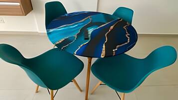 Una mesa redonda con una cubierta de mármol colorido rodeada de sillas color aguamarina con patas de madera.
