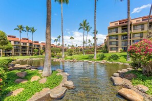 A resort with a pool, palm trees, and a golf course. - Kamaole Sands Top Floor 2BR Loft, Ocean View, Mountain View, Beach & Resort Pool (Kihei)