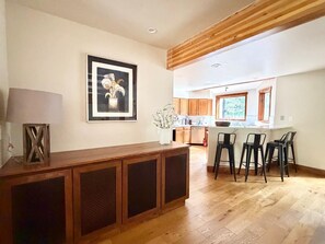 A kitchen with wooden cabinets, a dining area with bar stools, and a framed picture on the wall. - Beautiful 4BR on Vail Golf Course/Step to Bus Stop/Hot Tub (Vail)