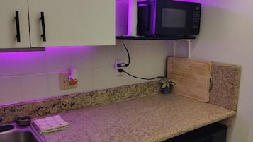 Eine Küche mit weißen Schränken, einer Granit Arbeitsplatte, einer Mikrowelle und einem Spülbecken.