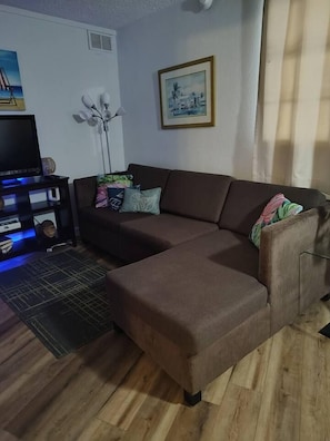 A living room with a brown sectional sofa, a black entertainment unit, and a framed picture on the wall.