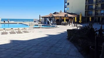 Ein Hotelinnenhof mit Schwimmbad, Sitzgelegenheiten im Freien und einem Gebäude mit mehreren Balkonen.