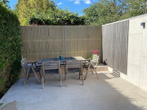 An outdoor patio with a wooden table and chairs, a potted plant, and a vertical wooden fence. - Het Demerhuys – a peaceful vacation home for 6, near Bokrijk and Hasselt (Diepenbeek)