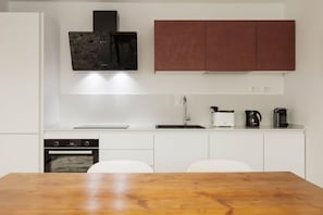 Eine moderne Küche mit weißen Schränken, einem Backofen, einer Kaffeemaschine und einem Spülbecken.