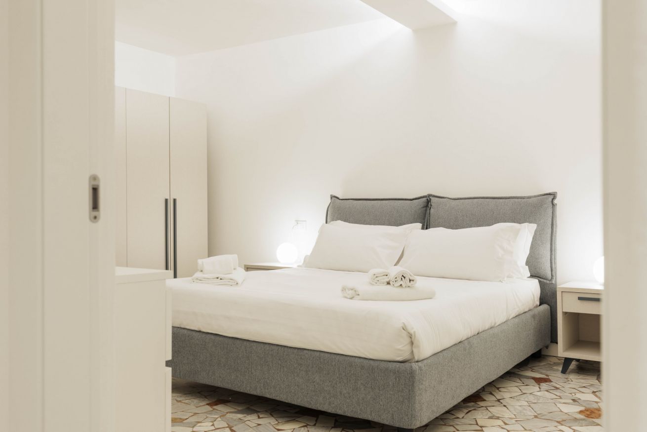 A bedroom with a bed, a nightstand, and a wardrobe.