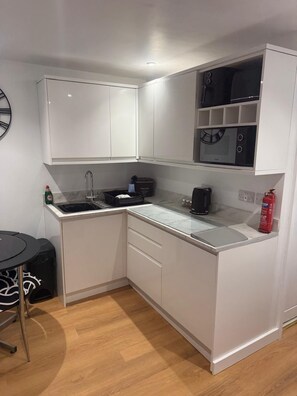 A compact kitchen with white cabinetry, a microwave, a sink, and a small dining area with a table and chairs.