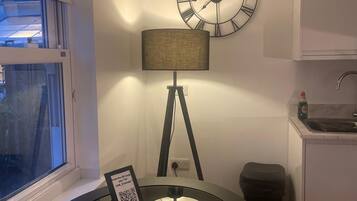 A modern kitchen with a round table, a wall clock, and a window.