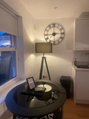 A modern kitchen with a round table, a wall clock, and a window.