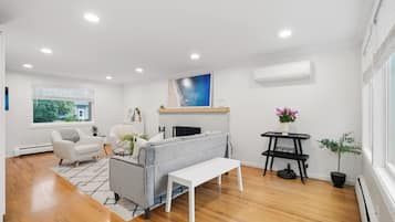 A modern living room with a grey sofa, white armchairs, a small white table, and a black coffee table.