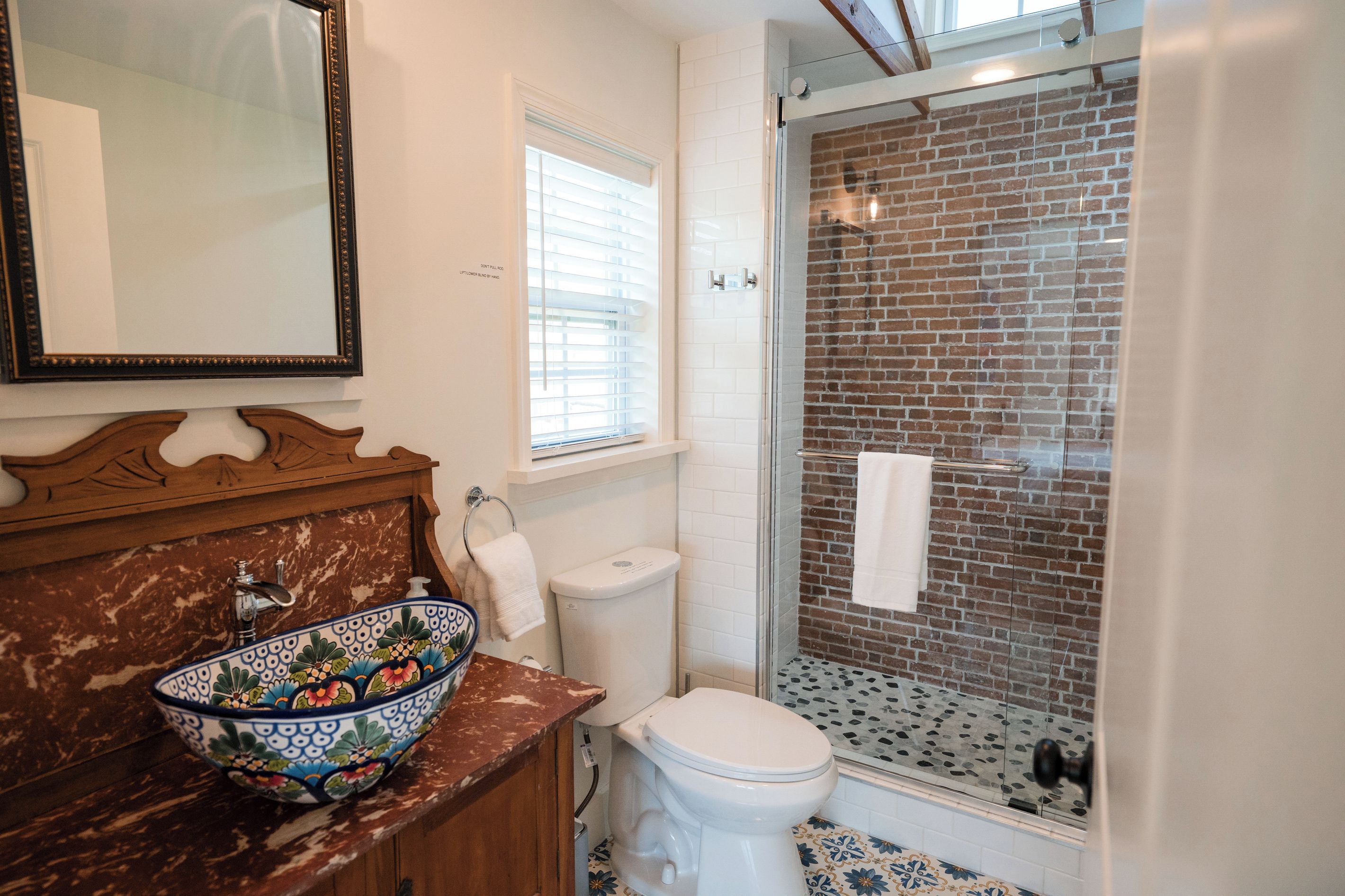 Une salle de bain avec un lavabo en marbre, des toilettes, une douche avec une porte en verre et un miroir au-dessus du lavabo.