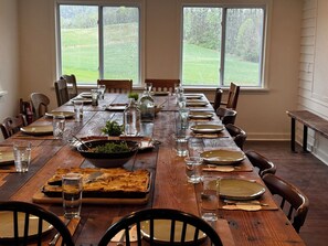 Une table à manger dressée pour un repas, avec des chaises, des assiettes, des verres et un centre de table.