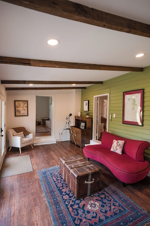 A living room with a red sofa, a wooden bench, a telescope, and a patterned rug.