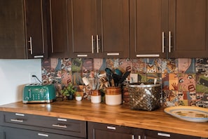 A kitchen with wooden cabinets, a green toaster, and a colorful backsplash.