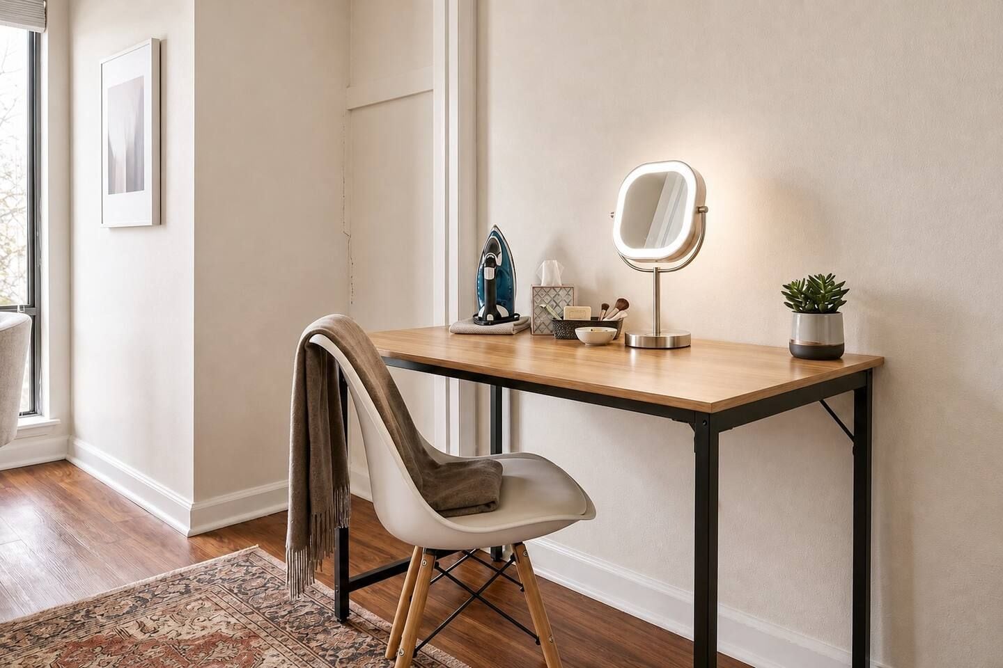 Une pièce comprenant un bureau en bois, une chaise, une petite plante en pot, un miroir et un tableau encadré accroché au mur.
