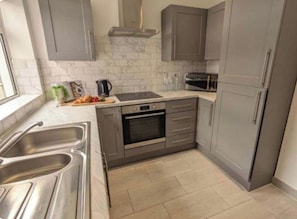 A modern kitchen with grey cabinets, a stainless steel sink, a built-in oven, and a microwave. - Carr Mill Stay | Free Parking | Shops & Transport (St Helens)