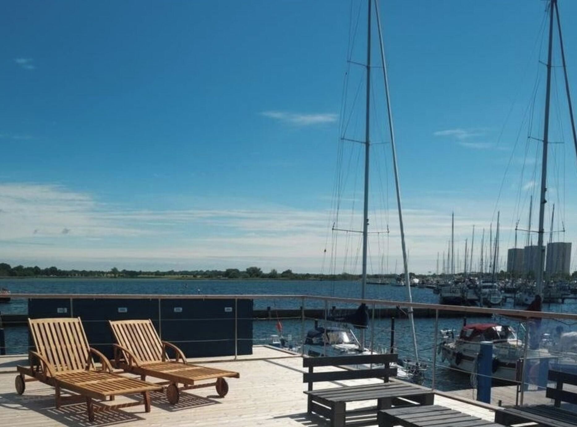 Un puerto deportivo con sillones de madera y una vista despejada del agua.