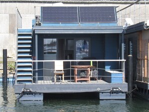 Une maison flottante dotée d’une terrasse, d’une table et d’une chaise.