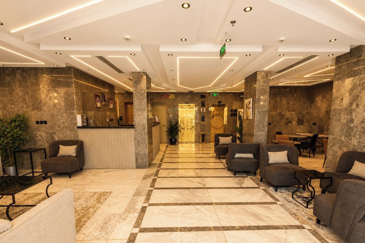 Un hall d’hôtel comprenant un comptoir d’accueil, un espace salon et un guichet d’enregistrement.