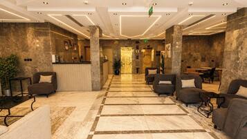 Una hall d'albergo con reception, area salotto e banco accettazione.