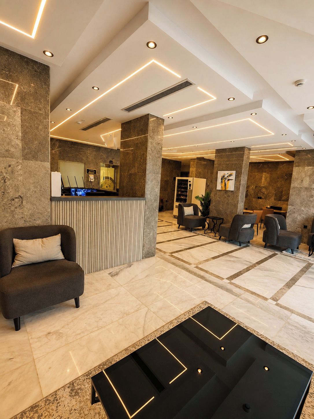 A modern lobby with a reception desk, seating area, and a patterned floor.