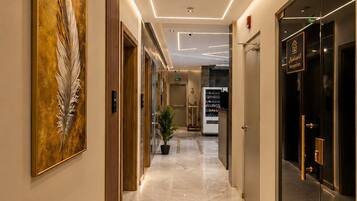 Un corridoio d'hotel con pavimento in marmo, una reception e un'ampia opera d'arte con piume a parete.