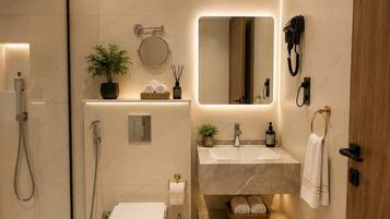 Un bagno moderno con doccia vetrata, un water, un lavandino con specchio e un porta asciugamani.