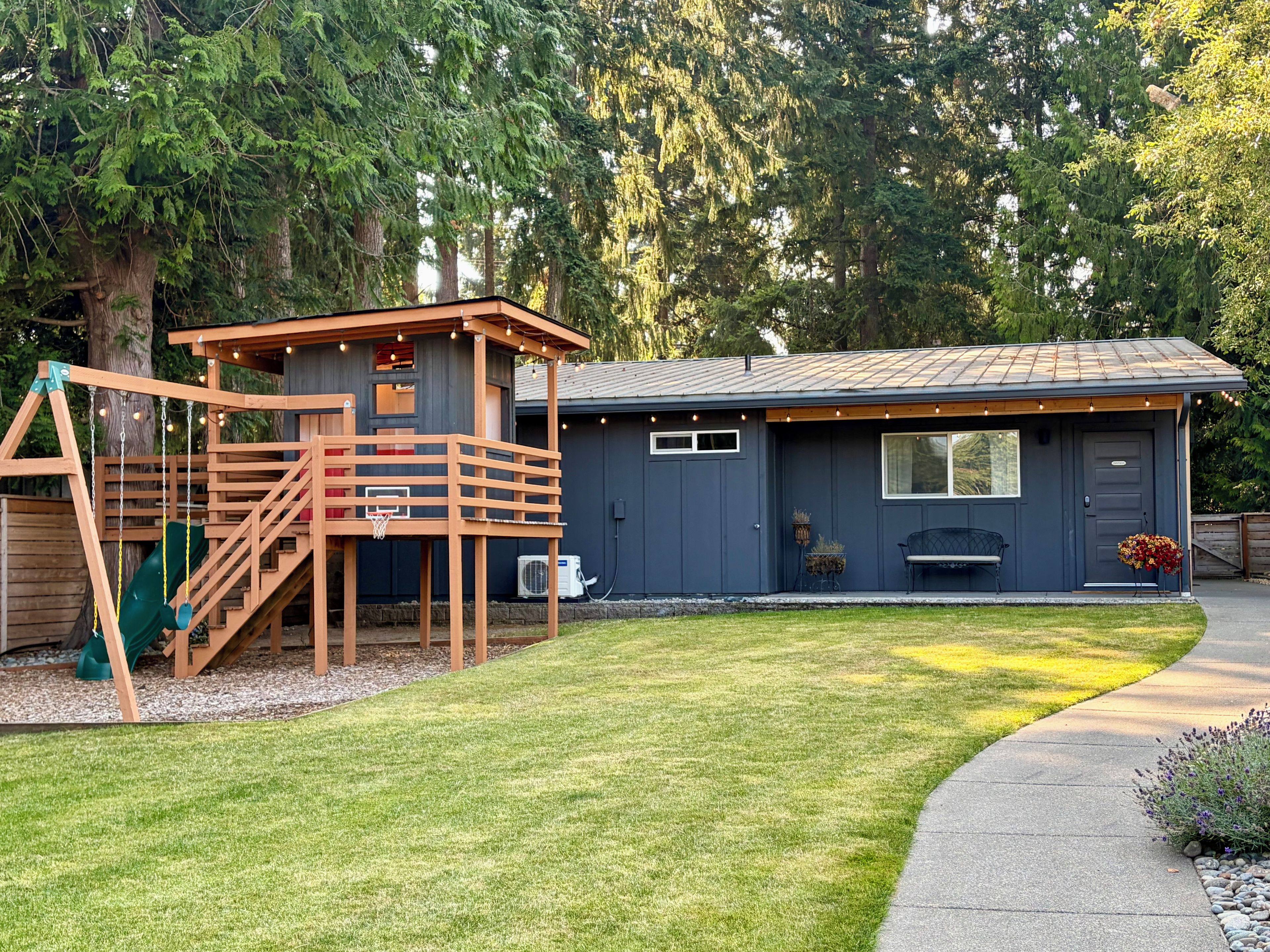 A residential property with a wooden play structure, a covered outdoor seating area, and a well-maintained lawn.