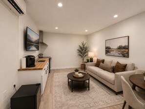 A modern living room with a sofa, coffee table, and a TV mounted on the wall. - Lake Sawyer Waterfront Retreat with Private Dock, Near Skiing and Mt. Rainier (Black Diamond)