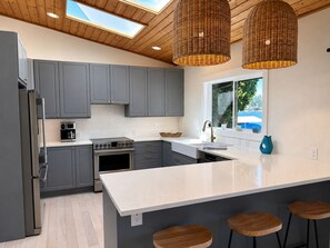 A modern kitchen with grey cabinets, a large island, and a window with a view. - Lake Sawyer Waterfront Retreat with Private Dock, Near Skiing and Mt. Rainier (Black Diamond)