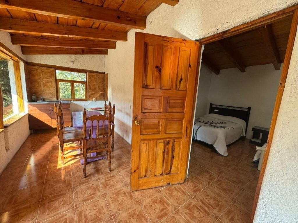 Una habitación con puerta de madera, una cama y una mesa con sillas.