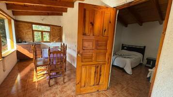 Una habitación con puerta de madera, una cama y una mesa con sillas.
