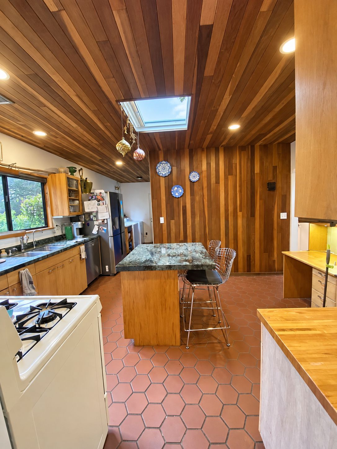 A modern kitchen with wooden paneling, a central island, and a skylight.