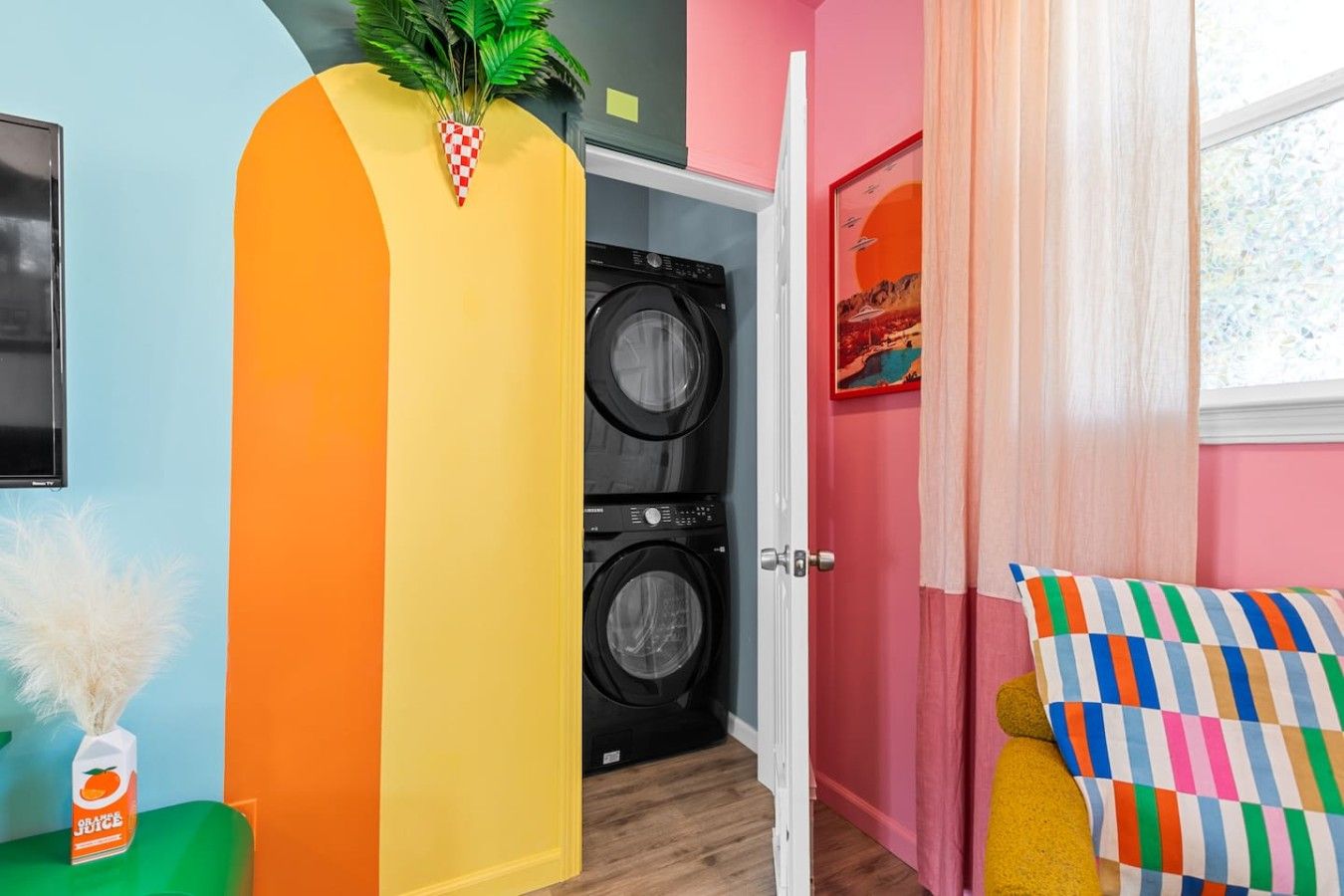 A laundry room with two washing machines, a door, and a colorful cushion.