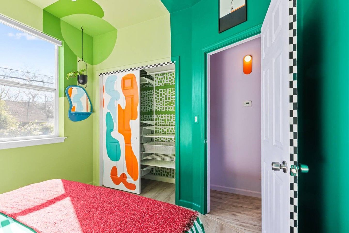 A room with a bed, a door with a checkered pattern, and a wall with a green and purple color scheme.