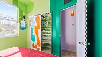 A room with a bed, a door with a checkered pattern, and a wall with a green and purple color scheme.