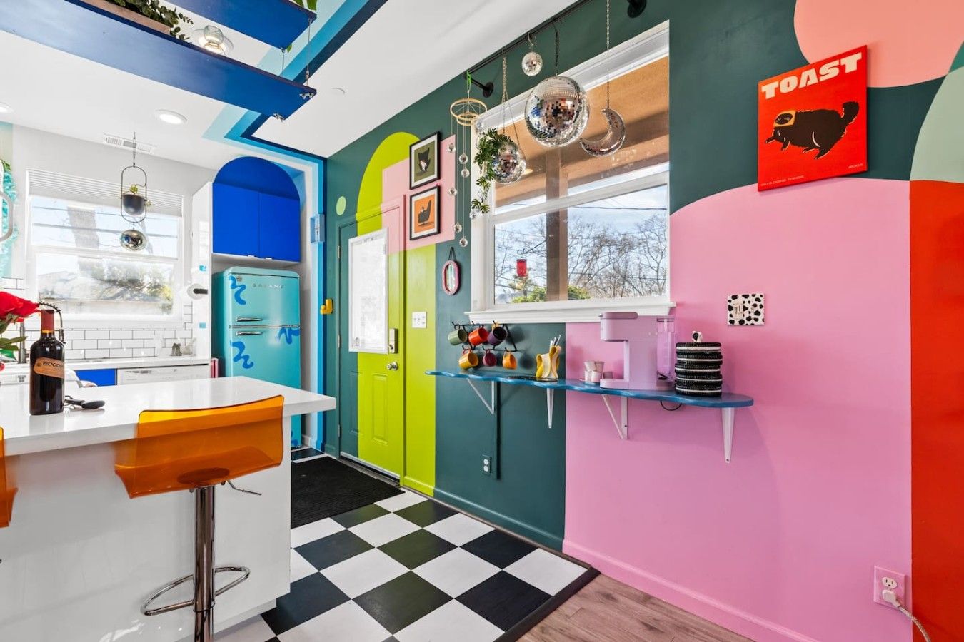 A vibrant kitchen with a bar area, colorful cabinets, and a disco ball.