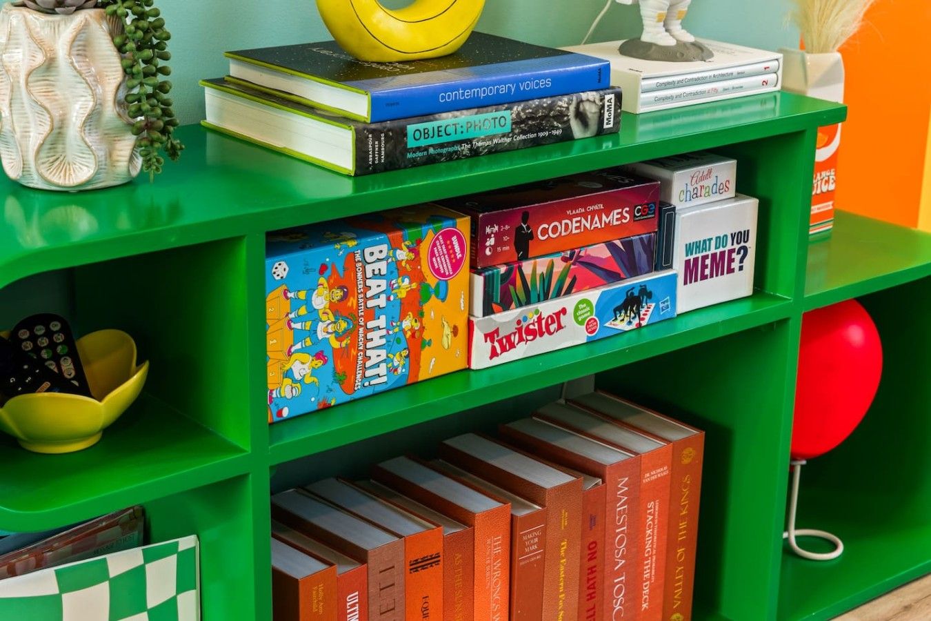 A bookshelf with various books and games, including 'Twister' and 'Codenames'.