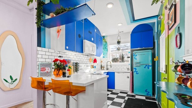 A modern kitchen with blue cabinets, a white island, and a checkered floor. - Colorful Retro Pop-Art Bungalow In Midtown (Sacramento)