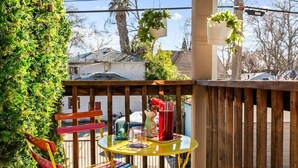 A wooden deck with a round table, chairs, and hanging planters. - Colorful Retro Pop-Art Bungalow In Midtown (Sacramento)