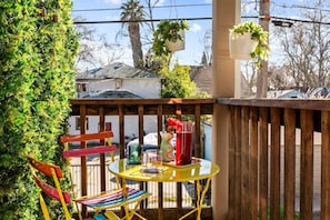 Eine Holzterrasse mit einem runden Tisch, Stühlen und hängenden Pflanzgefäßen.