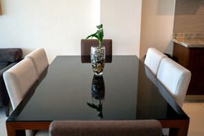 A dining table with a glass vase containing a plant, surrounded by upholstered chairs. - Oceanview 3-Bedroom Condo, Infinity Pool & Parking – Zona Dorada, Mazatlán (Mazatlán)