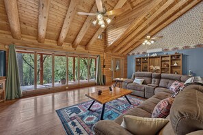 A spacious living room with wooden floors, a large sofa, a coffee table, and a fireplace. - Peaceful Log Cabin Getaway on 6 Private Acres (Grass Valley)